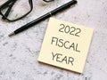 Text 2022 fiscal year written on sticky note with a pen.