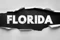 Text FLORIDA in distressed white bold font exposed through torn paper background. Creative typography art symbolizing the U.S. Royalty Free Stock Photo