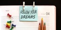 Text Follow your dreams on the stickers on the diary with office tools