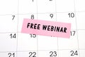 Text Free Webinar written on a pink sticky note posted on a calendar or planner page. Deadline concept read a reminder on calendar Royalty Free Stock Photo