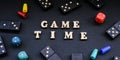 Text GAME TIME spelled out in wooden letter. Surrounded by dice, dominoes other game pieces on black background. Table games. Stay Royalty Free Stock Photo