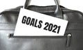 Text GOALS 2021 writing on white paper sheet in the black business bag. Business concept