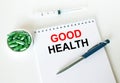 Text Good Health written in a notebook with a blue pen and a bunch of pills Royalty Free Stock Photo