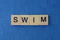 Text on gray word swim in small wooden letters