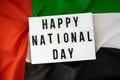 Text HAPPY NATIONAL DAY on background waving flag of UAE. National holiday of United Arab Emirates. Commemoration Day Royalty Free Stock Photo