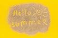 Text Hello Summer And Sun Sign Drawn On Sand On Yellow Paper Background. Creative Top View Concept Vacation