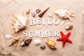 Text Hello Summer from white letters and sea shells and starfish on sand Royalty Free Stock Photo