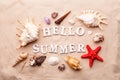 Text Hello Summer from white letters and sea shells and starfish on sand Royalty Free Stock Photo