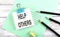 Text Help Others on the short note with pencils on the wooden background Royalty Free Stock Photo