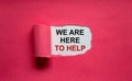 The text `we are here to help` appearing behind torn pink paper. Business concept. Copy space
