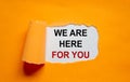 The text `we are here for you` appearing behind torn orange paper. Business concept. Copy space