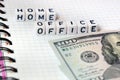 Text `Home Office`, word made of cubic letters and american money dollars on a white paper copybook background.
