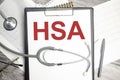 Text HSA-Health Savings Account on notebook with stethoscope and pen on wooden background Royalty Free Stock Photo