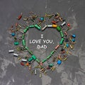 Text I love you, dad. Happy Fathers Day greeting card. Heart shape made from electronic components on gray concrete background.