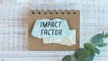 Text IMPACT FACTOR on a crafting notebook on a wooden background. Business concept Royalty Free Stock Photo