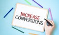 Text increase conversions on a notebook surrounded by colored felt-tip pens, business concept idea
