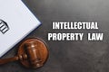 Text Intellectual Property Law, wooden judge`s gavel and book on grey background Royalty Free Stock Photo