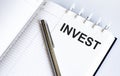 Text INVEST on the short note texture background with pen Royalty Free Stock Photo