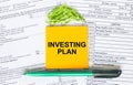 Text Investing Plan on note paper with pen, compass and paper clips Royalty Free Stock Photo