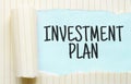 The text INVESTMENT PLAN appearing behind torn white paper Royalty Free Stock Photo