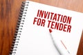 Text INVITATION FOR TENDER written in notepad, Office wood table from above, concept image for blog title or header image. Aged Royalty Free Stock Photo