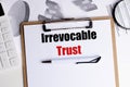 Text irrevocable trust on clipboard with financial documents, calculator and pen on desk Royalty Free Stock Photo