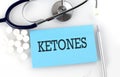 Text KETONES on a table with a stethoscope,pills and pen, medical concept