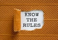 The text `know the rules` appearing behind torn brown paper. Beautiful background. Business concept