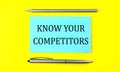Text KNOW YOUR COMPETITORS on the blue sticker on the yellow background Royalty Free Stock Photo