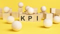 text KPI is written on wooden cubes. bright yellow surface. business concept. wooden sphere balls among the wood cubes Royalty Free Stock Photo