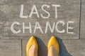 Text last chance written on gray sidewalk with women legs, top view