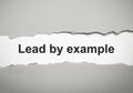 The text lead by example appearing behind torn grey paper Royalty Free Stock Photo
