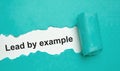 The text lead by example appearing behind torn grey paper Royalty Free Stock Photo