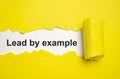 The text lead by example appearing behind torn grey paper Royalty Free Stock Photo