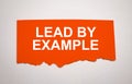 The text lead by example appearing behind torn grey paper Royalty Free Stock Photo