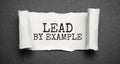 The text lead by example appearing behind torn grey paper Royalty Free Stock Photo