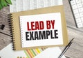 Text lead by example on notepad and pen on wooden background Royalty Free Stock Photo