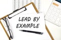 Text LEAD BY EXAMPLE on the white paper on clipboard with chart and calculator Royalty Free Stock Photo