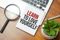 Text LEARN TO LOVE YOURSELF on torn paper on top of laptop keyboard Royalty Free Stock Photo