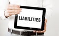 Text LIABILITIES on tablet display in businessman hands on the white background. Business concept