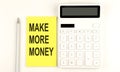 Text MAKE MORE MONEY on yellow sticker, next to pen and calculator Royalty Free Stock Photo