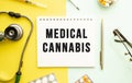 Text MEDICAL CANNABIS on notebook with stethoscope and pen on yellow background.