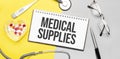 Text medical supplies on notebook with stethoscope,glasses, pen,thermometer, red pills and pen on yellow background. Medical Royalty Free Stock Photo