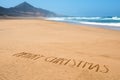 Text merry christmas in the sand of a beach