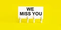 Text WE MISS YOU on white short note paper yellow background Royalty Free Stock Photo