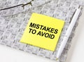 Text Mistake To Avoid on a yellow sticker lying on a notepad with eyeglasses and pen