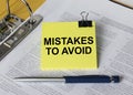Text Mistakes To Avoid on a yellow sticker that is in a folder with documents and a blue metal pen Royalty Free Stock Photo