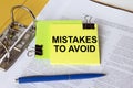 Text Mistakes To Avoid on a yellow sticker that is in a folder with documents and a blue pen Royalty Free Stock Photo