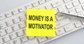 Text MONEY IS A MOTIVATOR on the keyboard on the white background