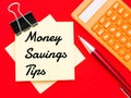 Text Money Savings Tips written on paper notes with pen and calculator isolated on red background.